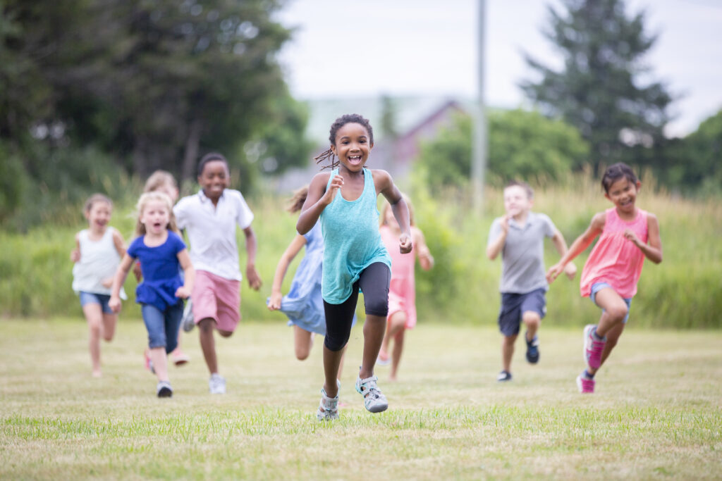A multi ethnic group of elementary age children are running outdoors