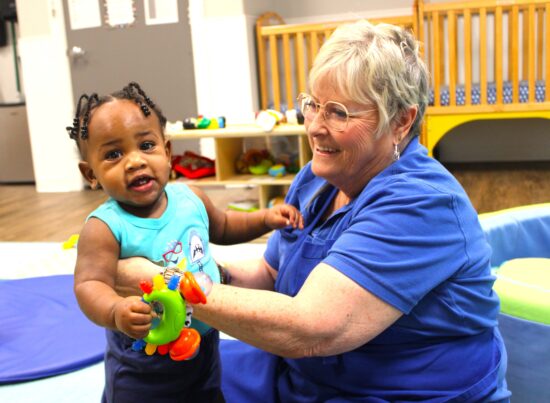 Teacher holding a child, smiling. 